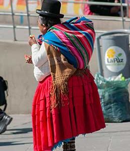 Cholita standing wearing a red skirt