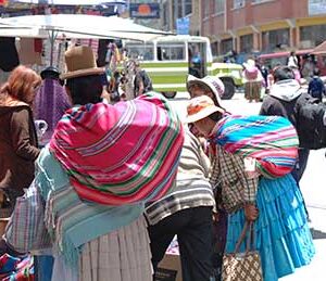 Cholita carries a cart of merchandise